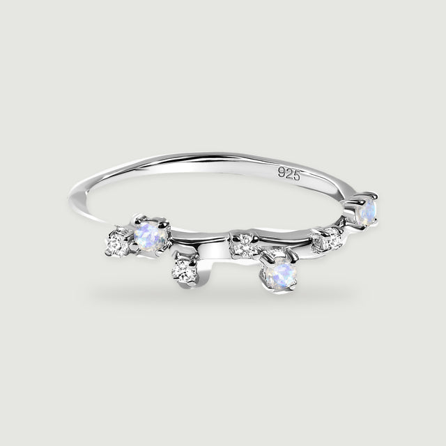A polished sterling silver ring has small blue-flashing round stones and clear accents along its curved band.