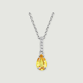 A silver-toned chain holds a yellow pear-shaped gemstone below a slim clear-stone bar on a pale gray surface.