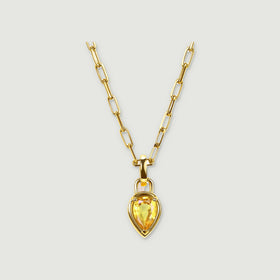 A yellow gold plated necklace has elongated chain links and a pear-shaped yellow citrine pendant against light grey.