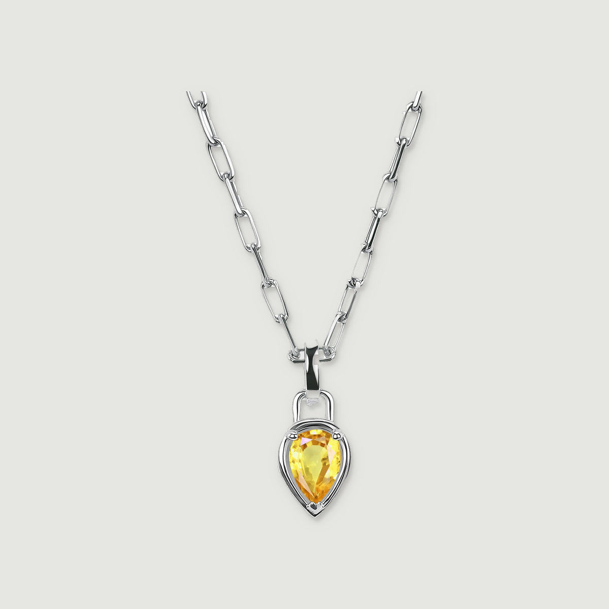 A white rhodium plated chain holds a pear-shaped citrine pendant on a pale grey background.