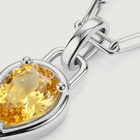 The silver-coloured pendant connector and rounded prongs sit beside sparkling yellow citrine facets.
