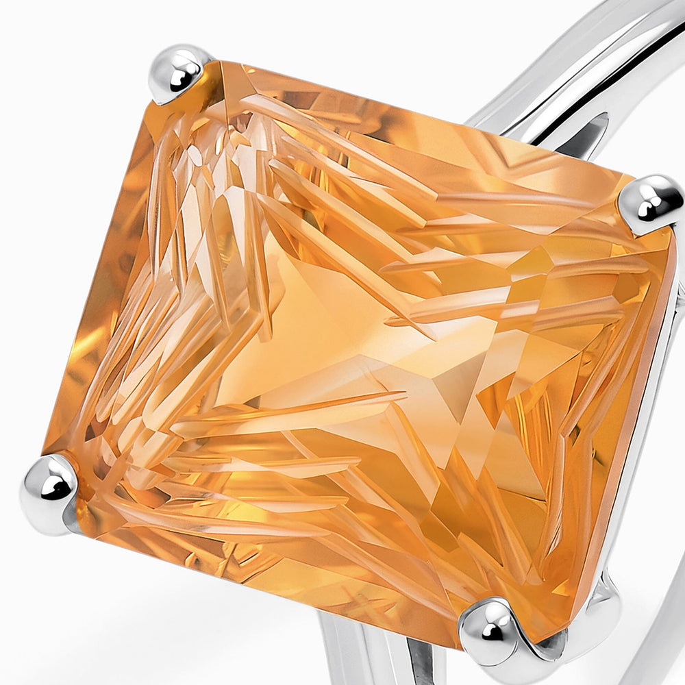 The angular facets of a golden citrine fill the frame between rounded silver corner prongs.