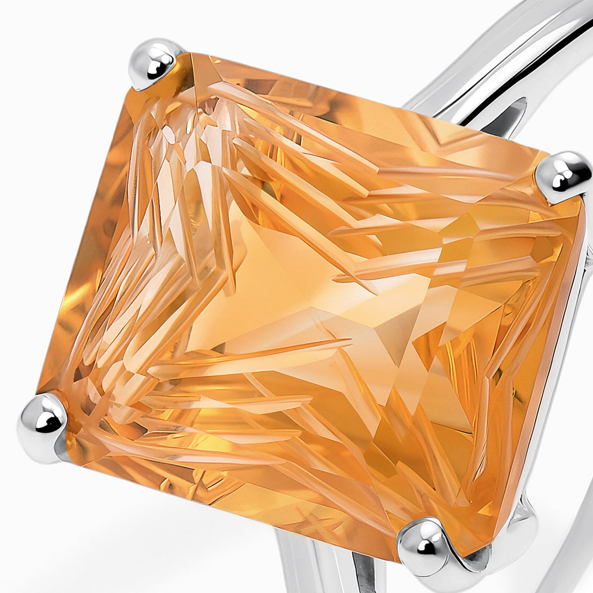 The angular facets of a golden citrine fill the frame between rounded silver corner prongs.