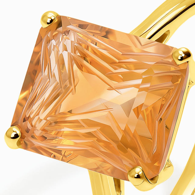 A close view shows the carved citrine facets and smooth yellow gold prongs beside the ring shoulder.