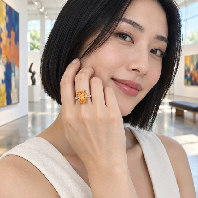 A woman with a black bob wears a silver citrine ring beside her cheek in a bright art gallery.