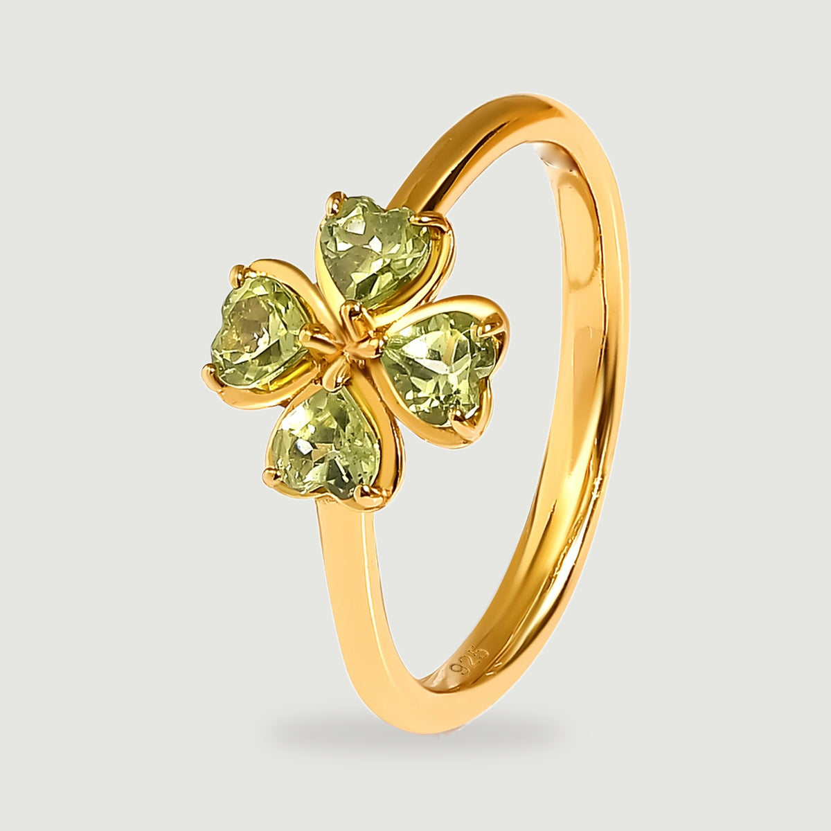 An angled yellow gold vermeil ring shows the slim band and raised heart-shaped peridot settings.