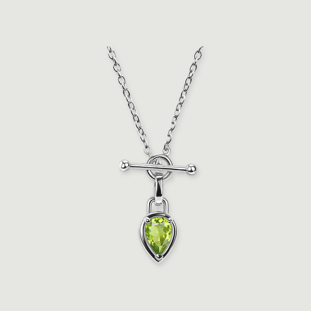 A silver-tone chain necklace has a green pear-shaped stone beneath a polished horizontal bar on a light grey background.