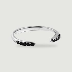 A sterling silver open band ring has rows of round black stones at both ends on a light gray surface.