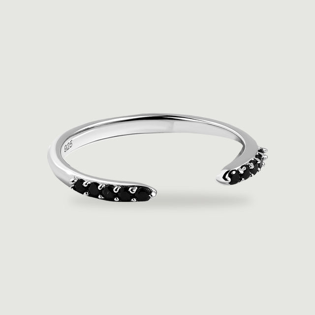 A sterling silver open band ring has rows of round black stones at both ends on a light gray surface.