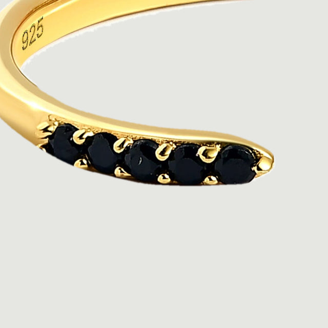 A close view shows the black stone row and polished yellow gold prongs at one end of the band.