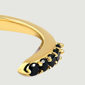 Black stones and yellow gold prongs follow the curve at the far end of the open band.