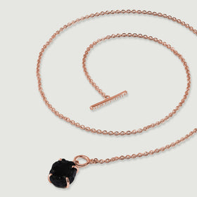 A rose gold vermeil chain curves across light gray beside an open front clasp and a rough black obsidian pendant.