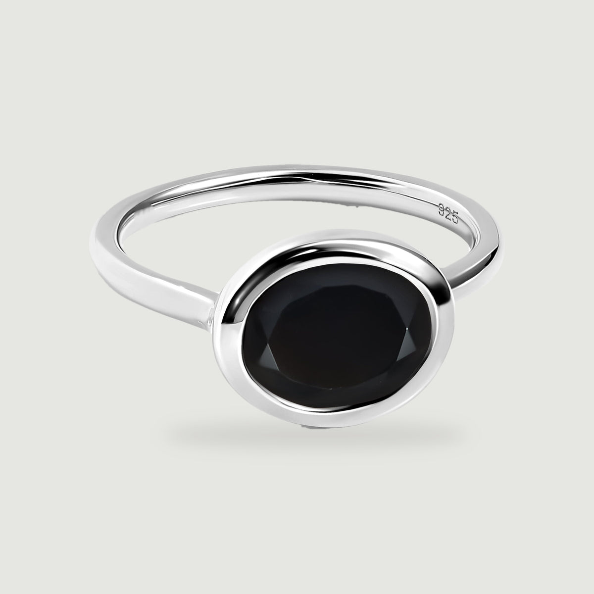 A sterling silver ring displays a black oval stone and polished round bezel on light gray.