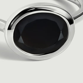 The black oval stone and curved sterling silver setting fill this close view.