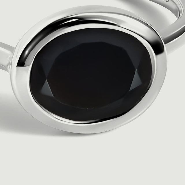 The black oval stone and curved sterling silver setting fill this close view.