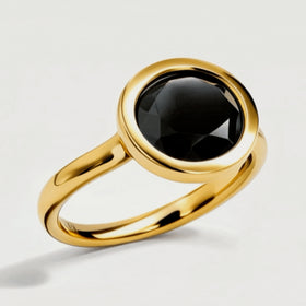 A tilted yellow gold vermeil ring reveals reflective black stone facets above its curved band.