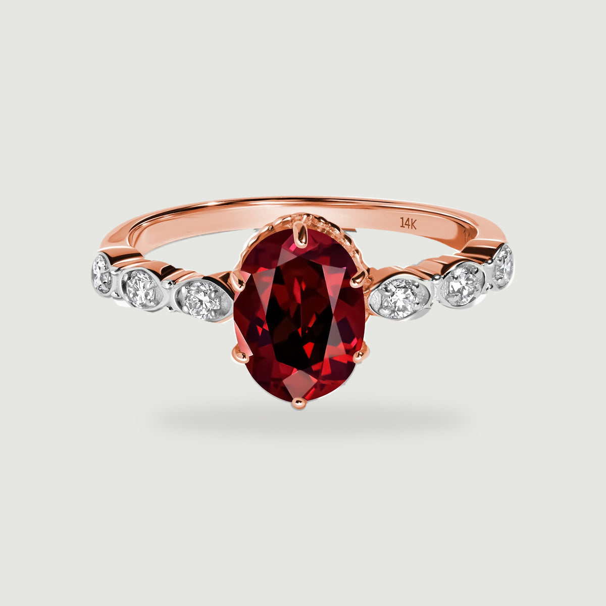 An oval deep red garnet sits between six round diamonds on a polished rose gold ring.