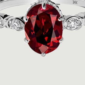 The oval garnet and graduated diamond shoulders are shown close up in white gold.
