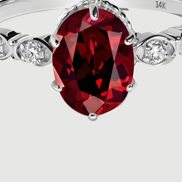 The oval garnet and graduated diamond shoulders are shown close up in white gold.
