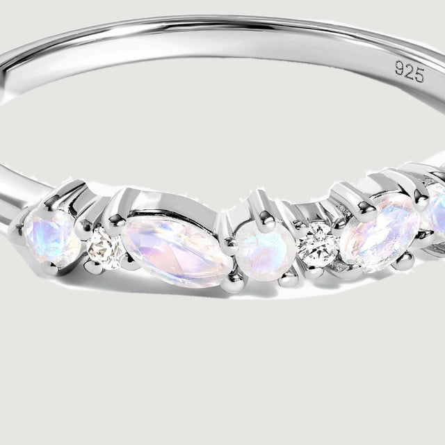 A close view shows milky iridescent stones held by silver prongs beside clear round stones.
