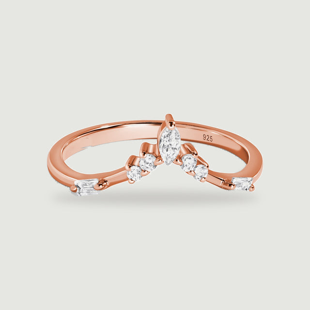 A rose gold ring with clear marquise, round and rectangular stones is centered on a light gray surface.