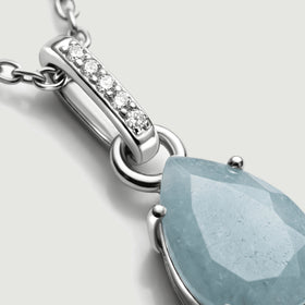 Five round clear stones line a polished silver bail above a connecting ring and the edge of a blue gemstone.