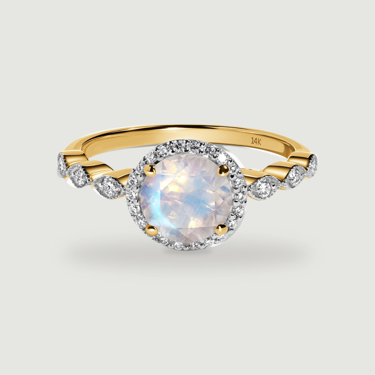 A yellow gold ring has a round iridescent moonstone, a diamond halo, and diamond-set shoulders.