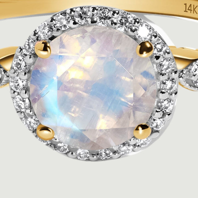 The faceted moonstone is held by four yellow gold prongs inside a circular diamond halo.