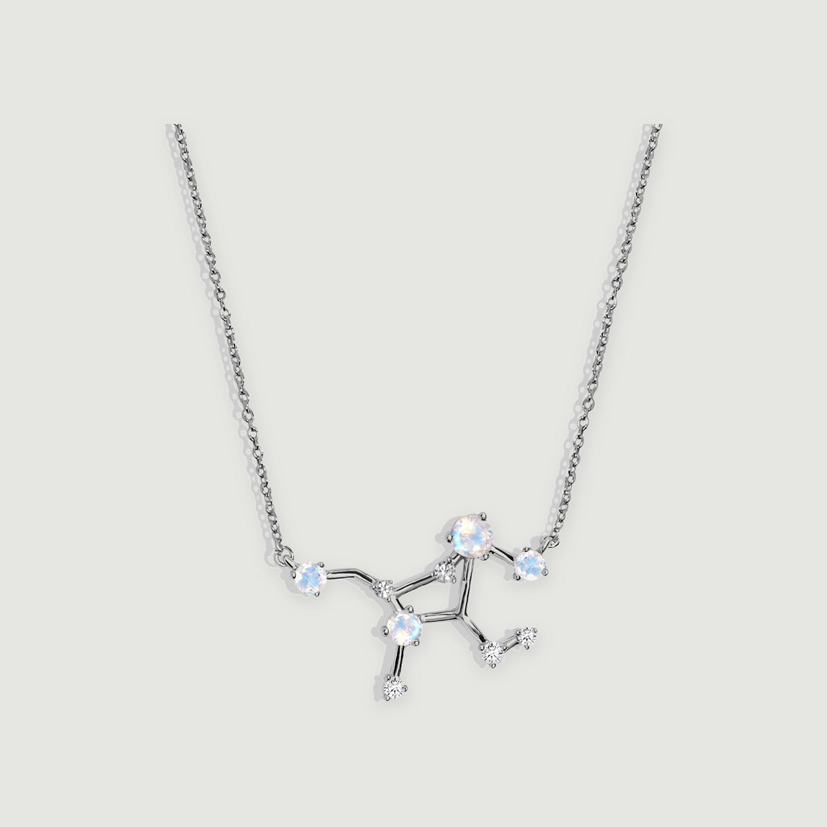 A sterling silver necklace with a branching pendant and four pale round moonstones rests on a light grey background.