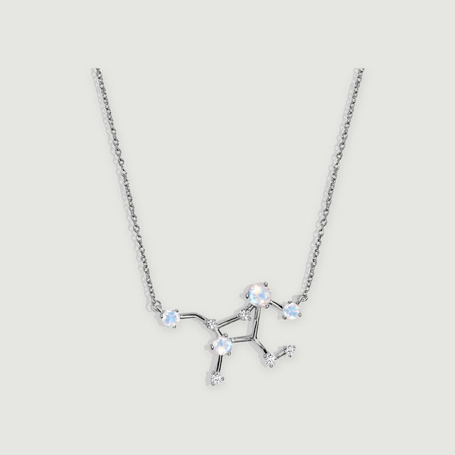 A sterling silver necklace with a branching pendant and four pale round moonstones rests on a light grey background.