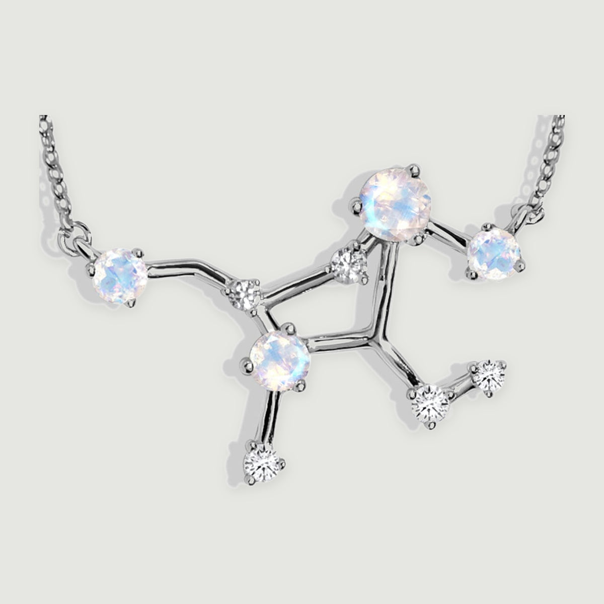 A close view shows silver prongs around four iridescent moonstones and clear accent stones on the branching pendant.