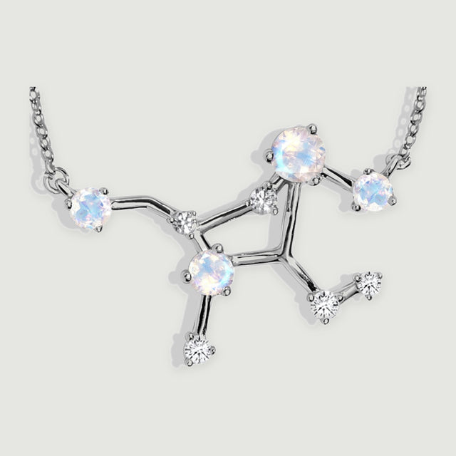 A close view shows silver prongs around four iridescent moonstones and clear accent stones on the branching pendant.