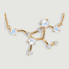 Polished yellow gold bars connect four round moonstones and clear accents in this close view of the pendant.