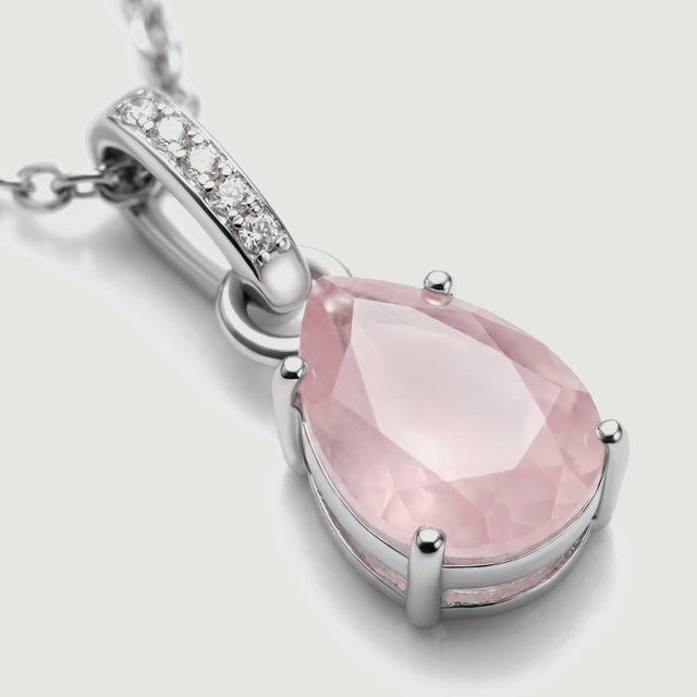A close view shows the pink gemstone facets, silver prongs, and five clear stones along the curved bail.