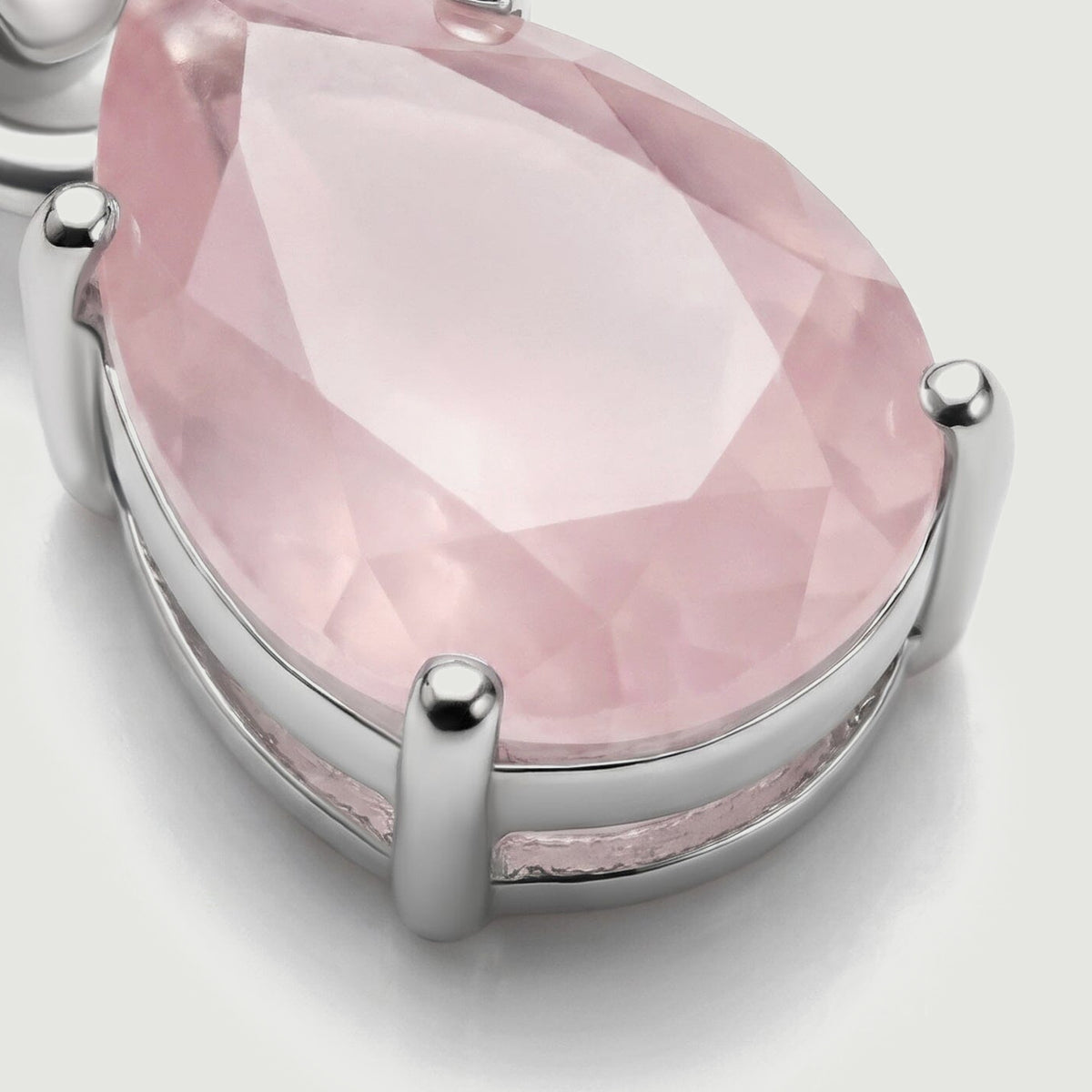 The lower side of the silver pendant reveals its open basket setting and rounded prongs around the pink stone.