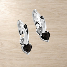 Heart-shaped black obsidian hoops photographed flat on a light surface