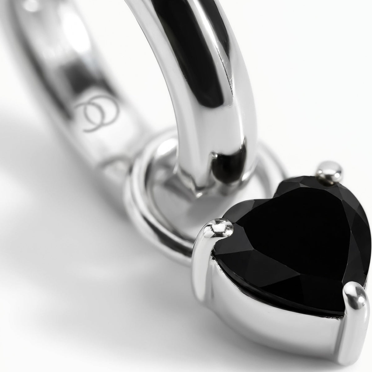 Rhodium-plated hoop with a heart-shaped black obsidian stone, close-up on white