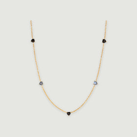 A yellow gold necklace has a central black heart and two pairs of heart-shaped stones along its curved chain.