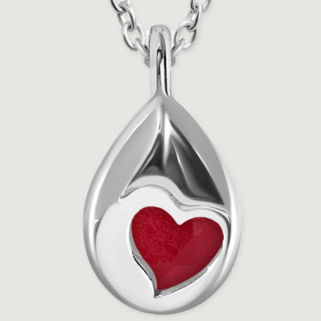 The polished silver back of a teardrop pendant reveals the pink gemstone through a heart-shaped cutout.