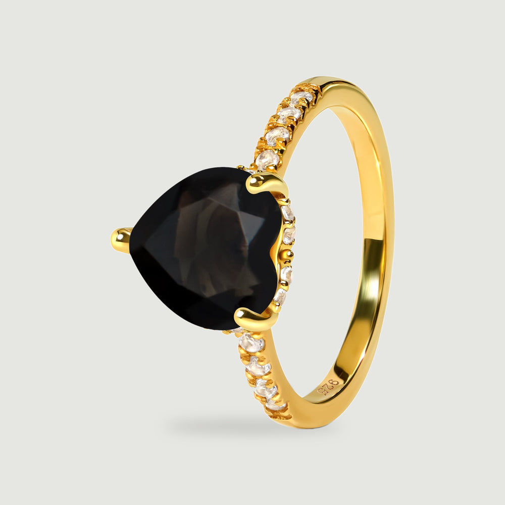 An angled yellow gold vermeil ring shows its black heart-shaped stone, raised prongs and curved band.