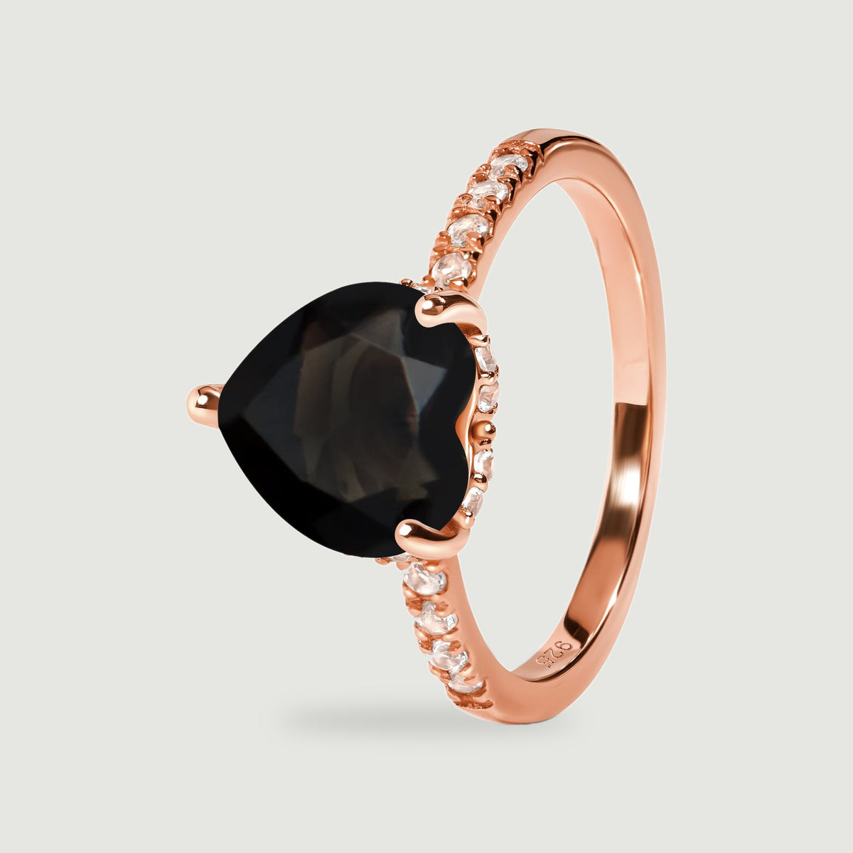 The rose gold vermeil ring is tilted to reveal the heart-shaped black stone and clear stones around its setting.