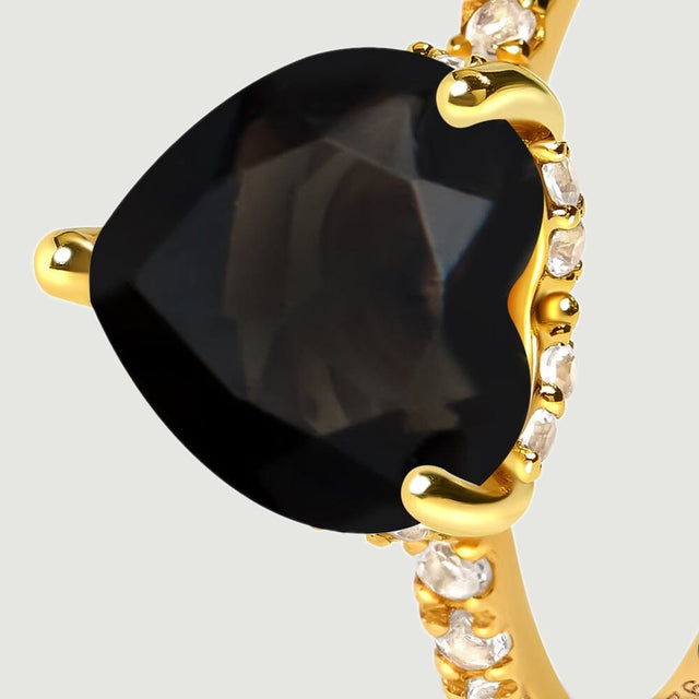 An oblique close-up reveals the black stone facets and clear accent stones beneath yellow gold claws.