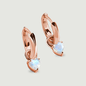 Rose-gold-tone hoop earrings show curved bands and pale blue heart-shaped stones on gray.
