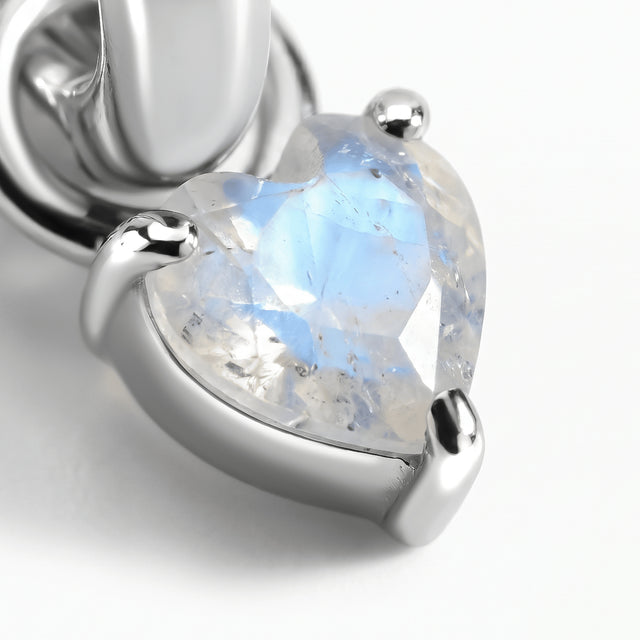 A close view shows blue reflections inside a heart-shaped moonstone held by silver-tone prongs.