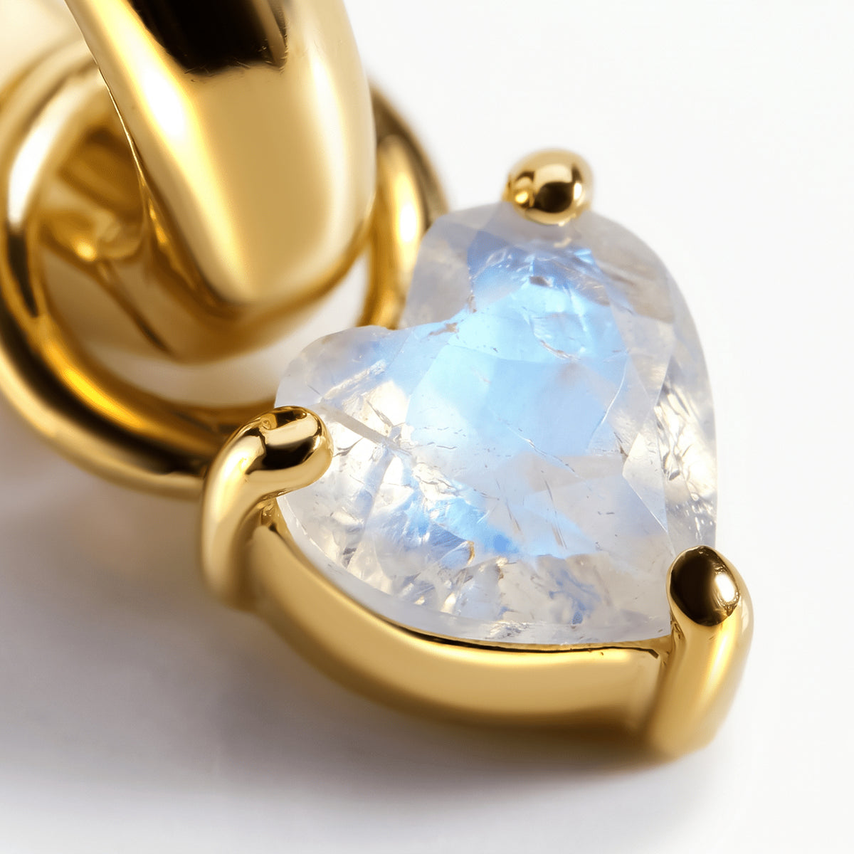Yellow-gold-tone prongs frame the faceted heart-shaped moonstone beneath a polished hoop.