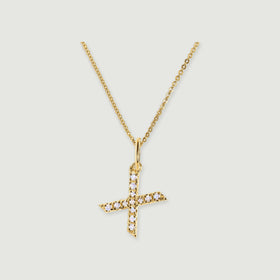 An X-shaped gold-tone pendant shows pale faceted stones along its crossing arms beneath a narrow bail.