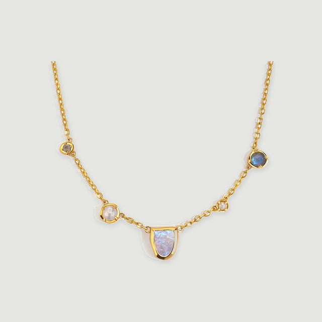 A gold-tone necklace has a shield-shaped moonstone center, two white pearls, and two round gray-blue stones.