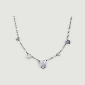 A silver-tone link necklace curves around a pale moonstone center with pearl and round stone accents.