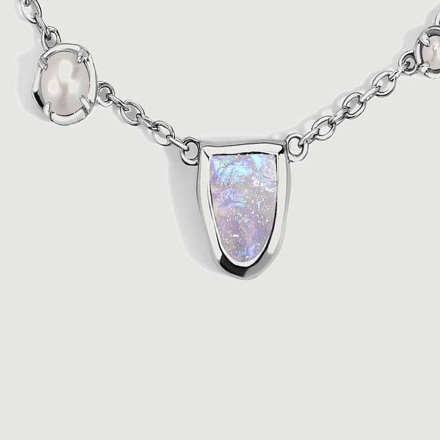A close view shows the textured moonstone surface, bright silver-tone rim, and neighboring pearls.