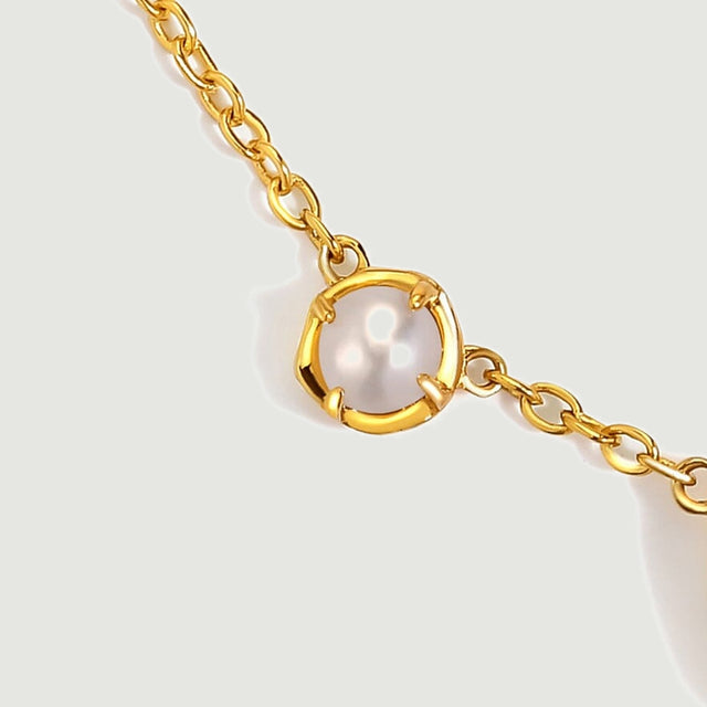 A round white pearl sits in gold-tone prongs between small oval chain links.